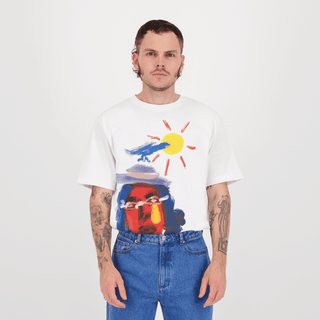 Homme posant dans un t-shirt blanc avec une illustration artistique de 'Mireille et son amie' par Encré. Détails colorés du design sur le t-shirt.