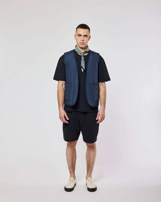 Modèle portant la veste sans manches Homecore - Repeat - Navy, associée avec un look décontracté pour la collection SS25.