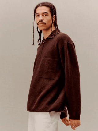 Un homme vêtue d'un pull marron à col montant et poche, posant dans un environnement neutre. Cette image capte l'essence de la collection Libertine-Libertine.