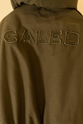 Vue arrière d'une veste avec le nom 'CALEB' brodé, représentant le style urbain et contemporain de la marque Caleb Paris.