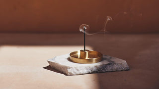 Un encensoir en laiton sur une pierre, avec de la fumée s'élevant, illustrant la collection Ichiko Ichie de parfums exquis et de senteurs naturelles.