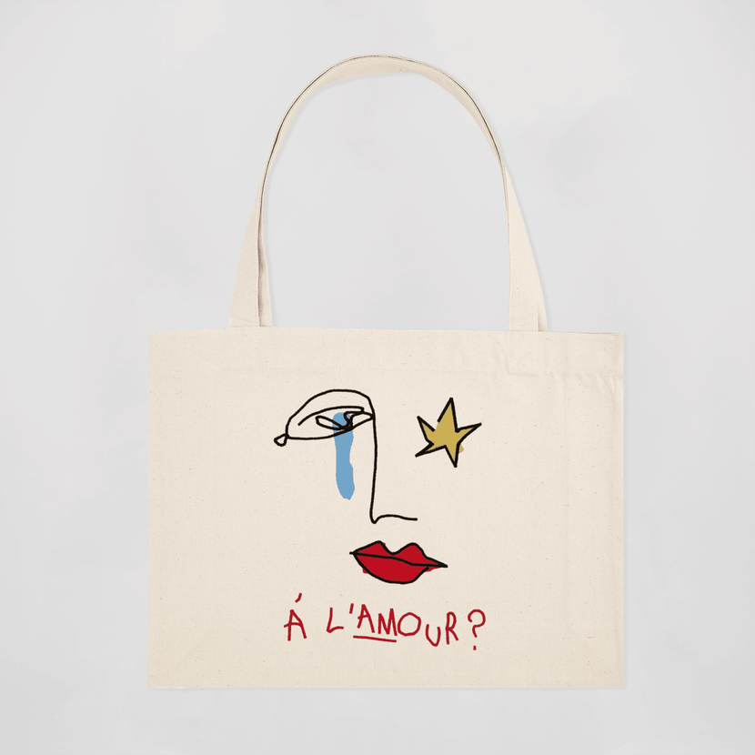Tote bag brodé "À l'amour" - beige de la marque Encré, affichant un design artistique avec un visage stylisé, des larmes bleues et des lèvres rouges sur fond beige.