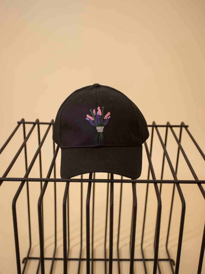 Casquette brodée 'bouquet' - noir de Caleb, affichée sur une étagère métallique, mettant en avant un motif floral coloré brodé sur le devant.