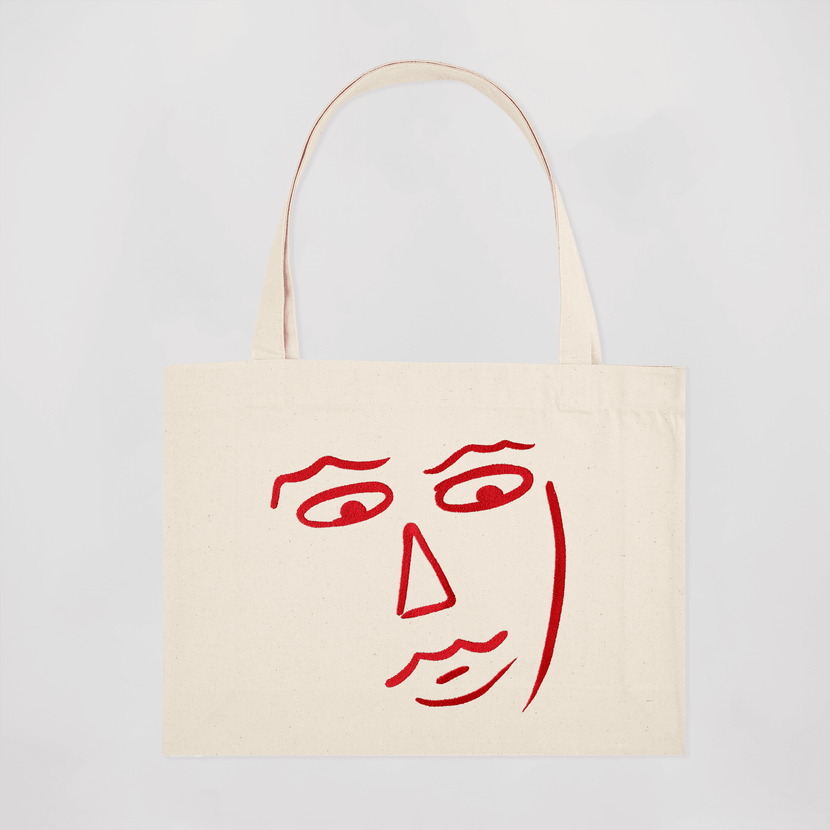 Tote bag beige avec un dessin rouge représentant un visage, conçu par Encré, modèle Gilles.