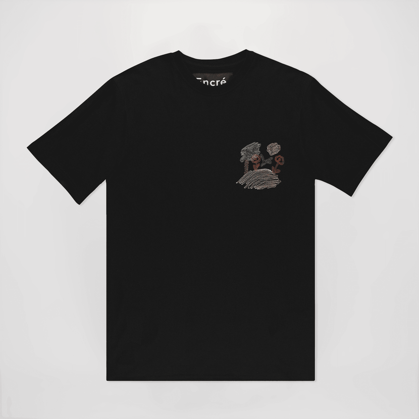 T-shirt brodé noir "La colline aux fleurs" d'encré, mettant en valeur un design coloré de fleurs et arbres brodés.