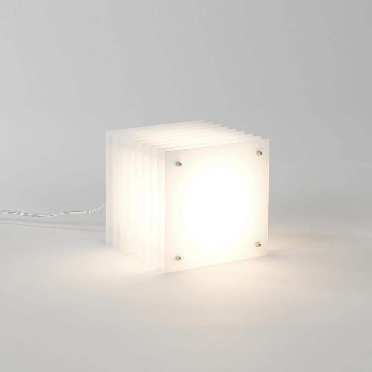 Lampe carrée blanche BANG Small Square Milky, illuminant une pièce avec une lumière douce.